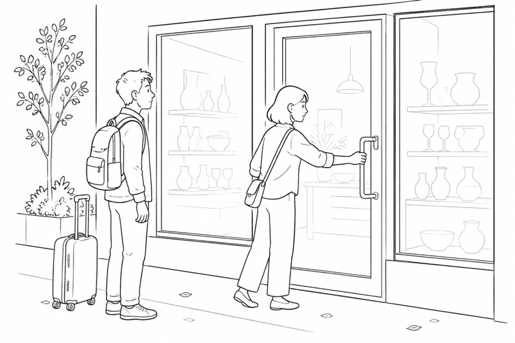 A traveler waits at a manual door as another person reaches for the handle.